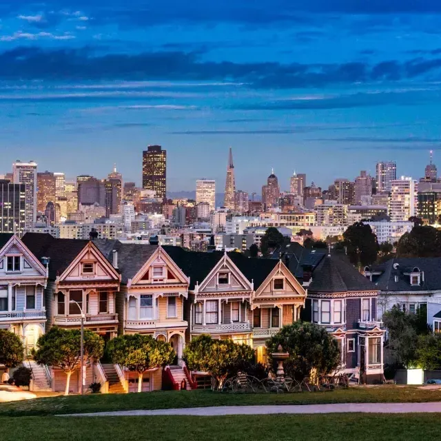 Les célèbres Painted Ladies d'Alamo Square sont photographiées devant l'horizon de San Francisco au crépuscule.